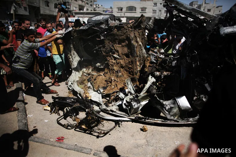 Palestinians inspect a car that was targeted in an Israeli air strike in Gaza City on June 27, 2014. An Israeli air strike killed two Palestinian militants and critically wounded a third in the Gaza Strip on Friday, the...