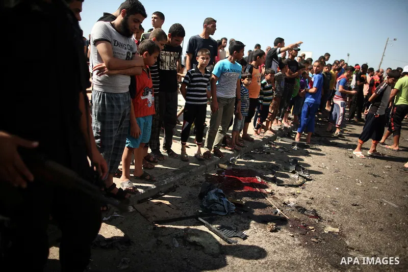 Palestinians inspect the site of a car that was targeted in an Israeli air strike in Gaza City on June 27, 2014. An Israeli air strike killed two Palestinian militants and critically wounded a third in the Gaza Strip on...