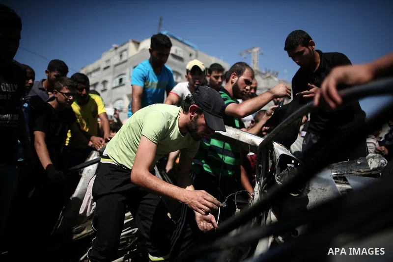 Palestinians inspect a car that was targeted in an Israeli air strike in Gaza City on June 27, 2014. An Israeli air strike killed two Palestinian militants and critically wounded a third in the Gaza Strip on Friday, the...