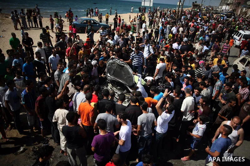 Palestinians inspect a car that was targeted in an Israeli air strike in Gaza City on June 27, 2014. An Israeli air strike killed two Palestinian militants and critically wounded a third in the Gaza Strip on Friday, the...