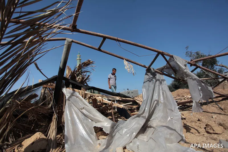 A Palestinian man inspects a land damaged in an Israeli air strike in the central Gaza Strip, on June 28, 2014. Israel's army launched airstrikes on southern and central Gaza early Saturday after projectiles fired from t...