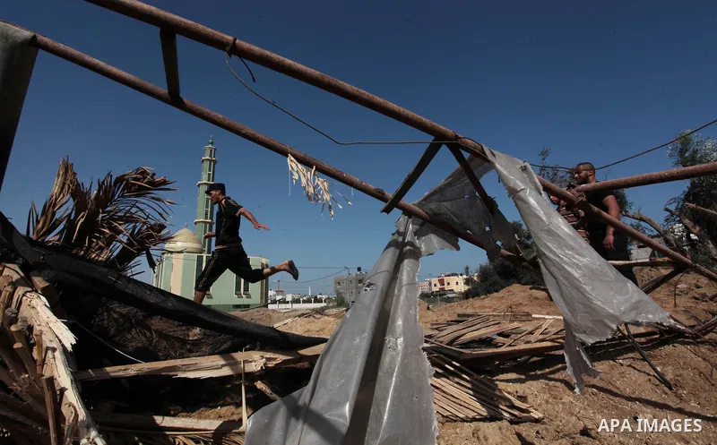A Palestinian man inspects a land damaged in an Israeli air strike in the central Gaza Strip, on June 28, 2014. Israel's army launched airstrikes on southern and central Gaza early Saturday after projectiles fired from t...