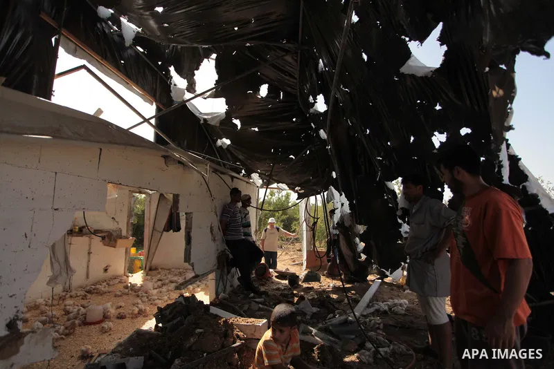 Palestinian men inspect a chicken coop damaged in an Israeli air strike in Bureij refugee camp in central Gaza Strip, on June 29, 2014. Israeli warplanes launched a series of air strikes across the Gaza Strip early Sunda...