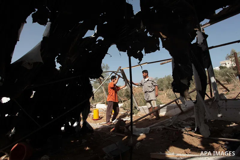 Palestinian men inspect a chicken coop damaged in an Israeli air strike in Bureij refugee camp in central Gaza Strip, on June 29, 2014. Israeli warplanes launched a series of air strikes across the Gaza Strip early Sunda...