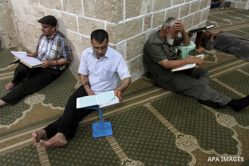 Palestinian muslims read the holy Qur'an at al-Omari mosque in Gaza city, on June 29, 2014. Muslims around the world refrain from eating, drinking and sexual intercourse from dawn till dusk during Ramadan, the holiest mo...