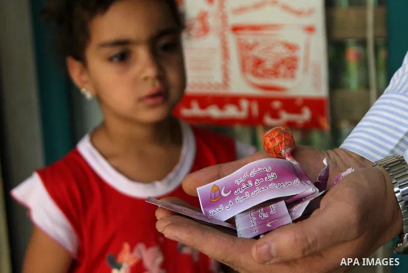 A Palestinian man carries sweets distributed by the Israeli army write "Ramadan Kareem few of the candy after Hamas makes the life badly in the Bank", which calls to incitement against Hamas, in the Balata refugee camp n...