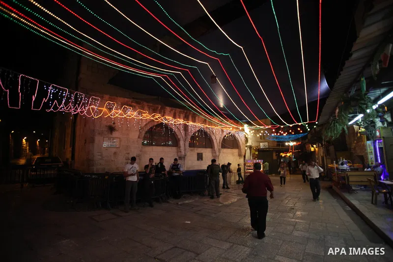 Palestinians walk under festive lights decorated an alley in Jerusalem's old city with during the first day of Muslim holy month of Ramadan, June 29, 2014. Muslim believers abstain from eating, drinking, smoking and havi...