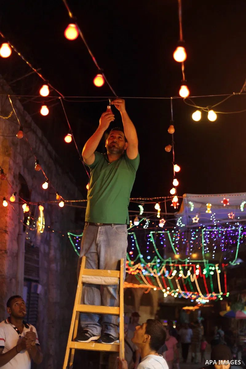 A Palestinian man decorates an alley of Jerusalem's old city with festive lights during the first day of Muslim holy month of Ramadan, June 29, 2014. Muslim believers abstain from eating, drinking, smoking and having sex...