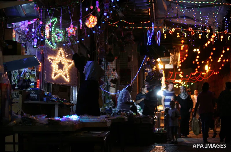 Palestinians walk under festive lights decorated an alley in Jerusalem's old city with during the first day of Muslim holy month of Ramadan, June 29, 2014. Muslim believers abstain from eating, drinking, smoking and havi...
