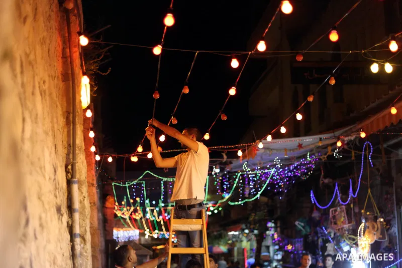 A Palestinian man decorates an alley of Jerusalem's old city with festive lights during the first day of Muslim holy month of Ramadan, June 29, 2014. Muslim believers abstain from eating, drinking, smoking and having sex...