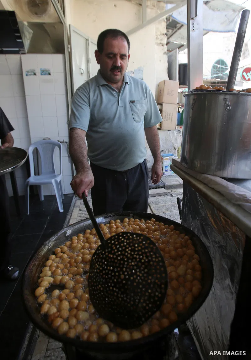 A Palestinian vendor sells fried dough ball sweets locally called "awwamah" at a shop on the Muslim holy month of Ramadan in the West Bank city of Nablus on Sunday, June 30, 2014. Muslims throughout the world are celebra...