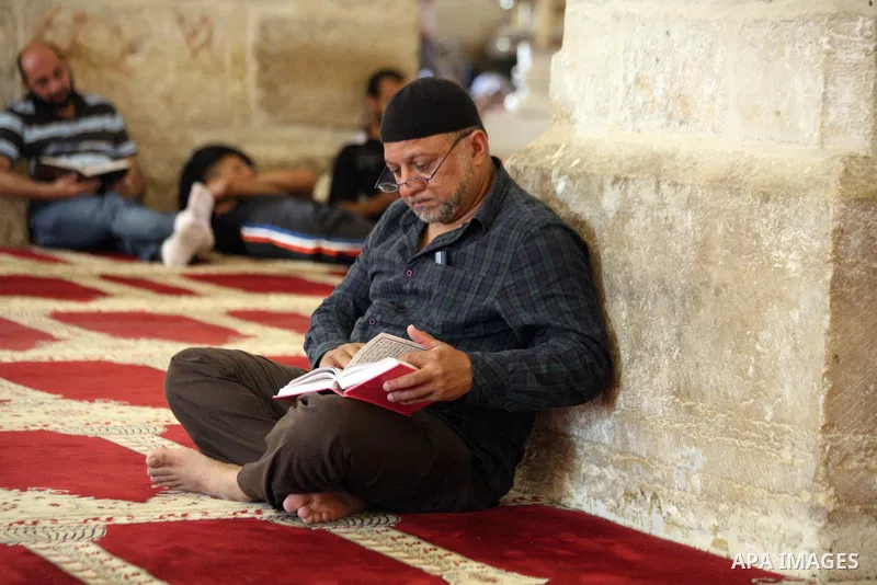 A Palestinian man reads the Qur'an during the holy fasting month of Ramadan at al-Aqsa mosque, Islam's third holiest site, in Jerusalem's Old City on June 30, 2014. Muslim believers abstain from eating, drinking, smoking...