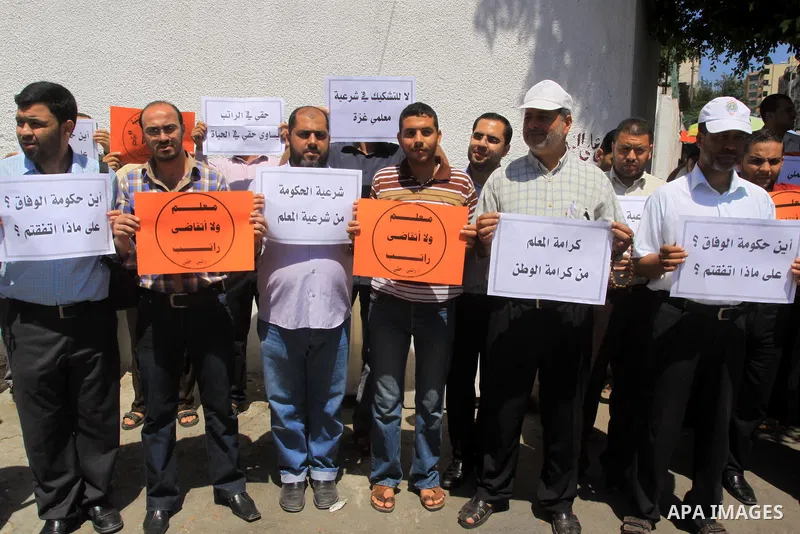 Palestinian Teachers hold placards during a protest against not receiving their salaries, in Gaza City on July 01, 2014. Many issues involving the Strip, such as the fate of former employees of the Hamas government, have...