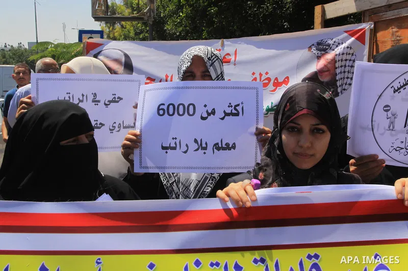 Palestinian Teachers hold placards during a protest against not receiving their salaries, in Gaza City on July 01, 2014. Many issues involving the Strip, such as the fate of former employees of the Hamas government, have...