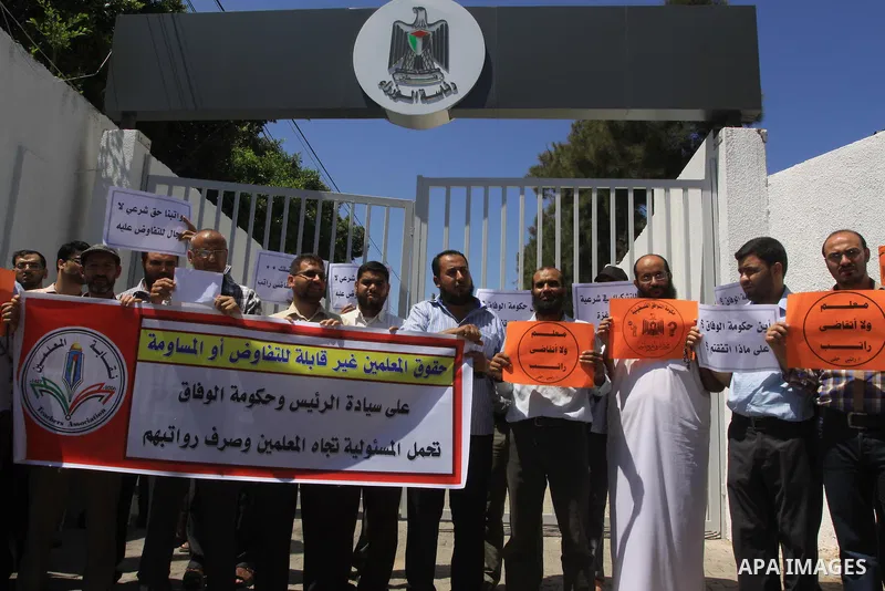 Palestinian Teachers hold placards during a protest against not receiving their salaries, in Gaza City on July 01, 2014. Many issues involving the Strip, such as the fate of former employees of the Hamas government, have...