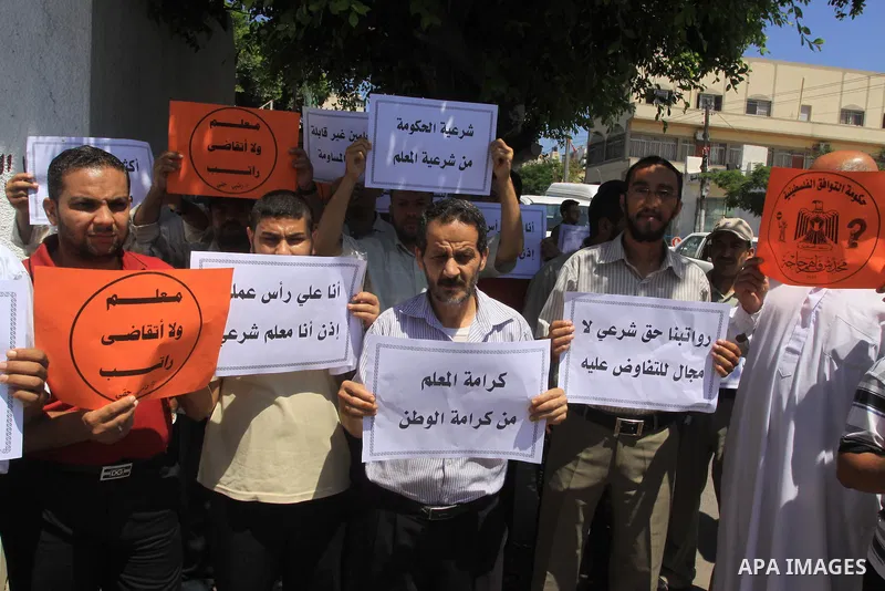 Palestinian Teachers hold placards during a protest against not receiving their salaries, in Gaza City on July 01, 2014. Many issues involving the Strip, such as the fate of former employees of the Hamas government, have...
