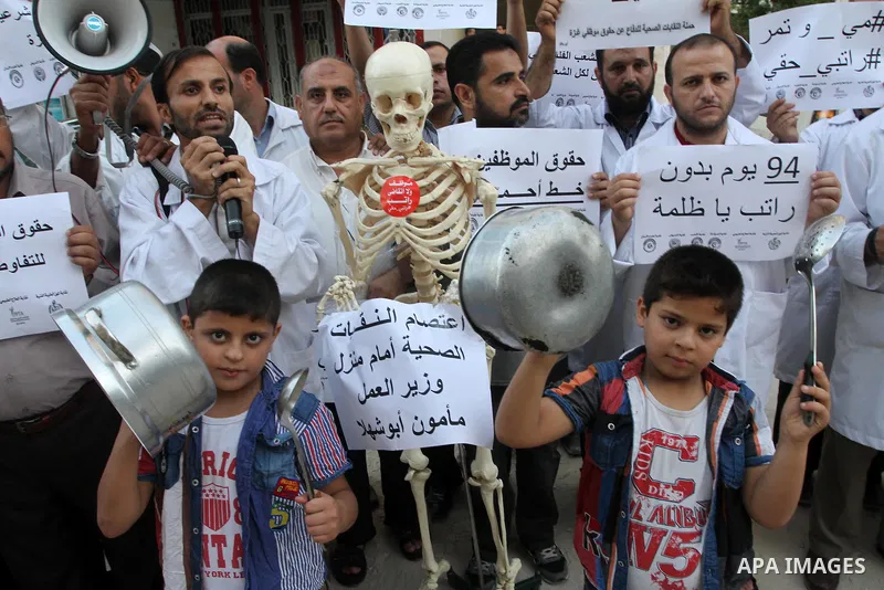 Palestinian employees of the former government in Gaza Strip hold placards during a protest against not receiving their salaries, in front of the home of Minister of Labor Mamoun Abu Shahla, in Gaza City on July 03, 2014...