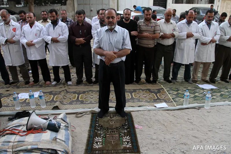 Palestinian employees of the former government in Gaza Strip pray during a protest against not receiving their salaries, in front of the home of Minister of Labor Mamoun Abu Shahla, in Gaza City on July 03, 2014. Many is...