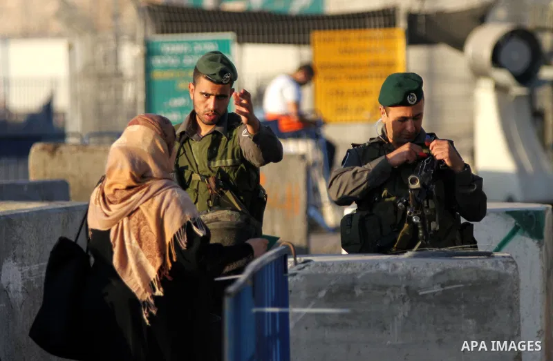 An Israeli security officer prevents a Palestinian woman from crossing through the Qalandia checkpoint between Ramallah and Jerusalem, in the occupied West Bank, to reach the al-Aqsa mosque compound in Jerusalem's Old Ci...
