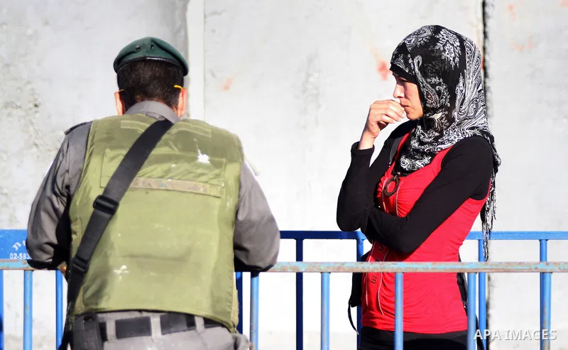 A Palestinian women presents her identity card to an Israeli border police officer as she waits to make her way through the Qalandia checkpoint between Ramallah and Jerusalem, in the occupied West Bank, to reach the al-A...