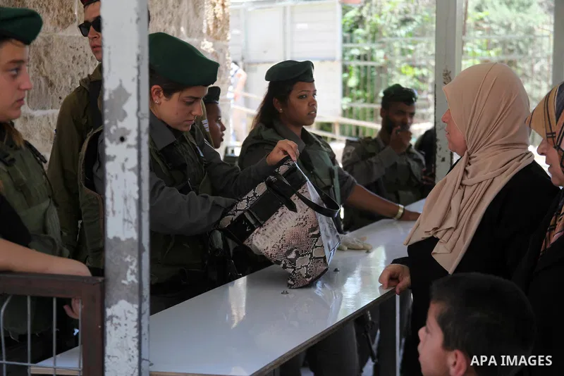 An Israeli police officer searches the bag of a Palestinian woman before reach the Ibrahimi mosque "Sanctuary of Abraham" to the traditional Friday prayers, the first of Islam's holy month of Ramadan, in the West Bank Ci...