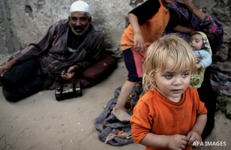 A Palestinian poor family sit outside their home in Beit Lahiya, northern Gaza Strip, July 5, 2014. Muslims around the world are observing the holy fasting month of Ramadan in which they refrain from eating, drinking, se...