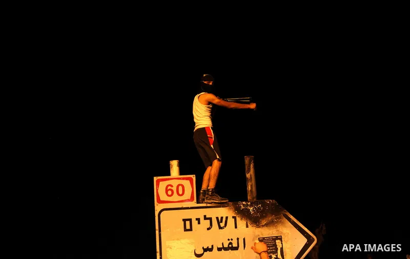 A Palestinian stone thrower hurls stones at Israeli security forces during clashes in a protest against the murder of a Palestinian teenager, on July 7, 2014 in the West Bank village of Al-Ram, adjacent to Israeli-annexe...