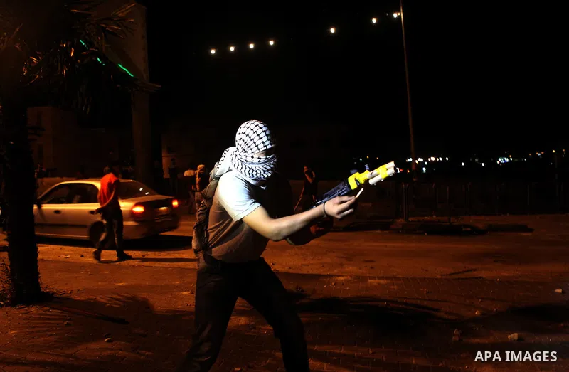 A Palestinian protestor directs fireworks toward Israeli security forces during clashes in a protest against the murder of a Palestinian teenager, on July 7, 2014 in the West Bank village of Al-Ram, adjacent to Israeli-a...
