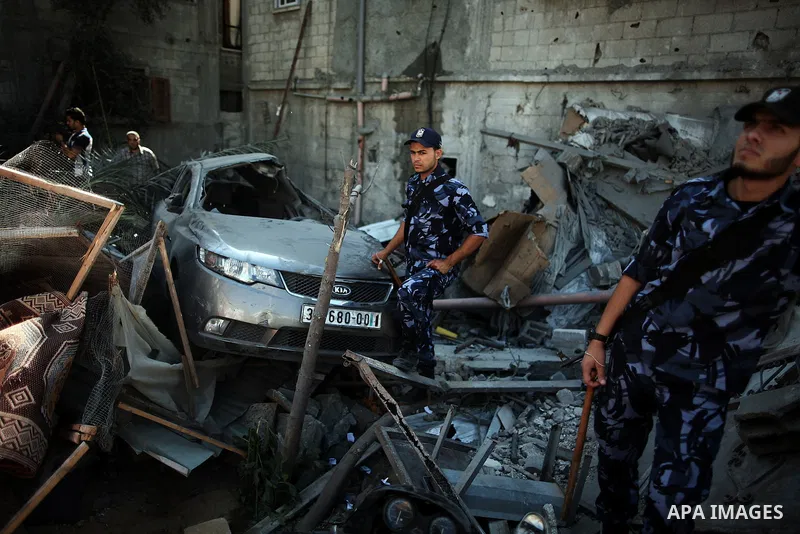 Policemen take charge as Palestinians search for bodies at a house, which police said was destroyed in Israeli air strikes, in Khan Younis in the southern Gaza Strip July 8, 2014. At least six Palestinians were killed an...
