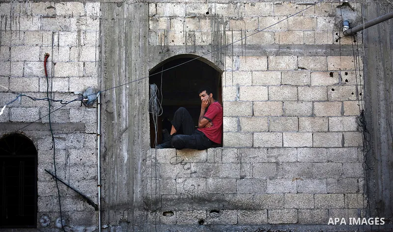 A Palestinian man looks on a house as members of the civil defense (not seen) search for bodies at a house, which police said was destroyed in Israeli air strikes, in Khan Younis in the southern Gaza Strip July 8, 2014....