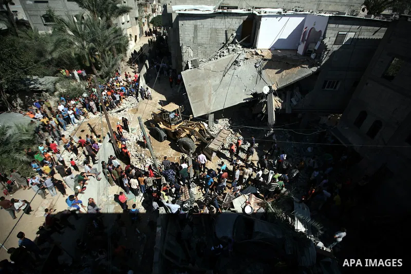 Palestinians gather around a house which police said was destroyed in Israeli air strikes in Khan Younis in the southern Gaza Strip July 8, 2014. At least six Palestinians were killed and about 25 wounded in an Israeli a...