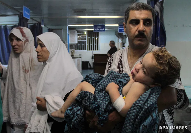 A Palestinian man carries an injured girl at Al-Shifa hospital after Israeli air strikes in Gaza City, on July 12, 2014. 15 Palestinians were killed during the last strike of the night. Photo by Khaled Al-Sabbah
