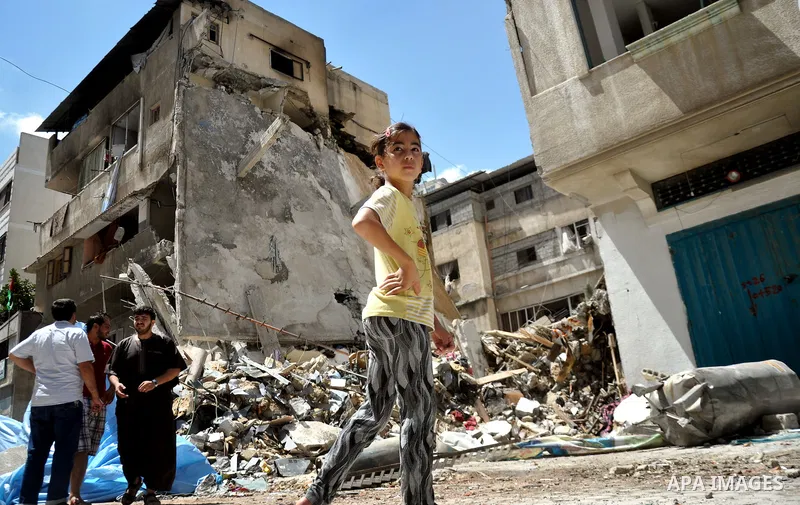 Palestinian children look at the remains of a house which destroyed in an Israeli airstrike in Gaza City July 14, 2014. Israel appeared to hold off on a threatened escalation of its week-old Gaza Strip barrage on Monday...