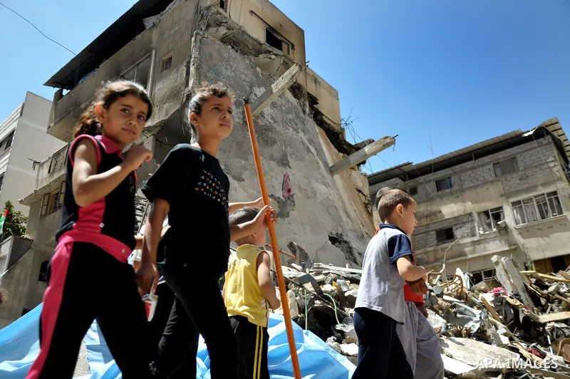 Palestinian children look at the remains of a house which destroyed in an Israeli airstrike in Gaza City July 14, 2014. Israel appeared to hold off on a threatened escalation of its week-old Gaza Strip barrage on Monday...