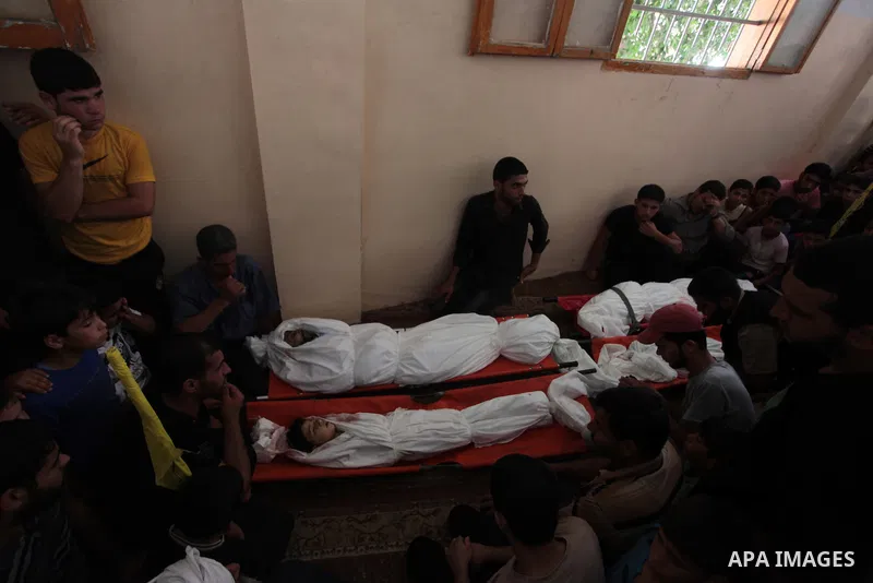 Palestinian mourners and family members mourn over the bodies of four members of the Al-Astal family, who were killed following an Israeli air strike which took place before a five-hour humanitarian truce, during a funer...