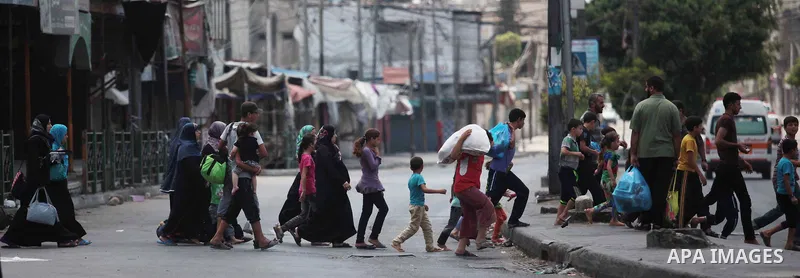 Palestinians who flew from the Shuja'iyya neighbourhood walk on a street in east Gaza City, 20 July 2014. Tens of thousand of Palestinians living in the area which is in close proximity left their houses in the past days...