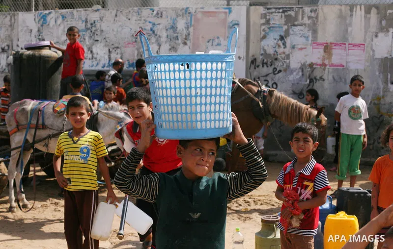Palestinians fill bottles and containers with water from a public tap in in Khan Yunis, in the southern Gaza Strip July 21, 2014. Israeli forces killed at least 10 Palestinian militants on Monday after they crossed the b...