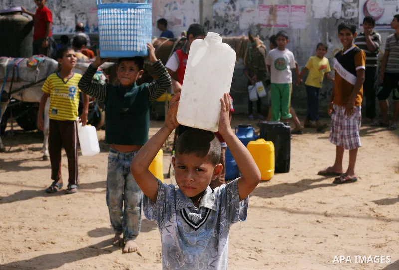 Palestinians fill bottles and containers with water from a public tap in in Khan Yunis, in the southern Gaza Strip July 21, 2014. Israeli forces killed at least 10 Palestinian militants on Monday after they crossed the b...