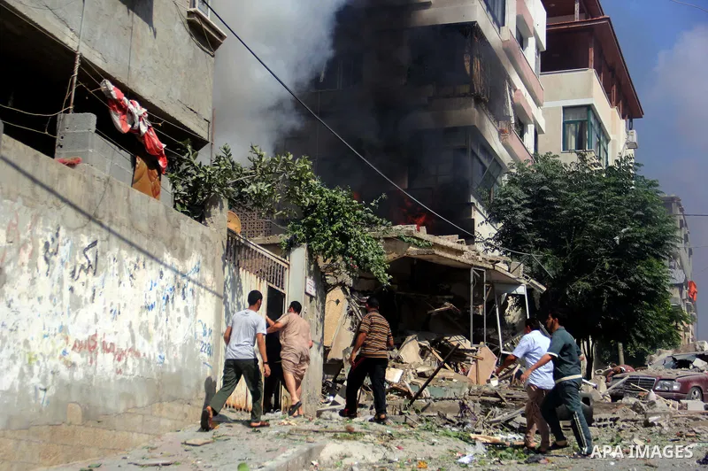 Palestinians watch as smoke rises from a destroyed building following an Israeli air strike at al-Shatee refugee camp, in Gaza City on July 21, 2014. The Palestinian death toll in an Israeli offensive in the Gaza Strip j...