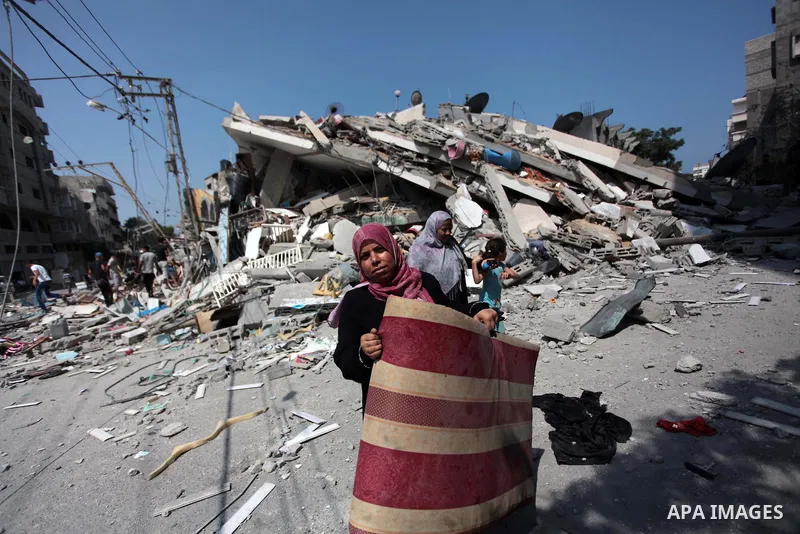 A Palestinian woman holds belongings through the rubble of a residential building, which police said was destroyed in an Israeli air strike, in Gaza City July 22, 2014. Israel kept up its assaults in the Gaza Strip on Tu...