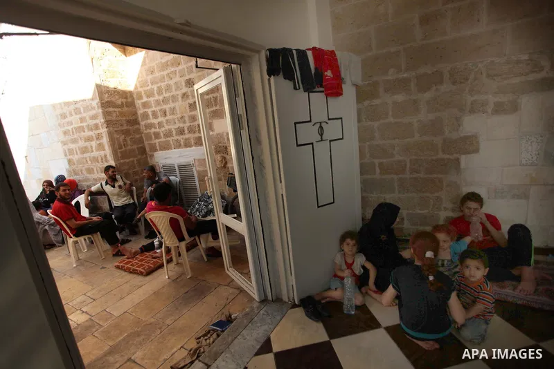 Displaced Palestinian women and children sit in a Greek Orthodox church where many Palestinians are taking shelter in Gaza City on July 23, 2014. For the first time in years, Gaza City's Greek Orthodox church is packed t...