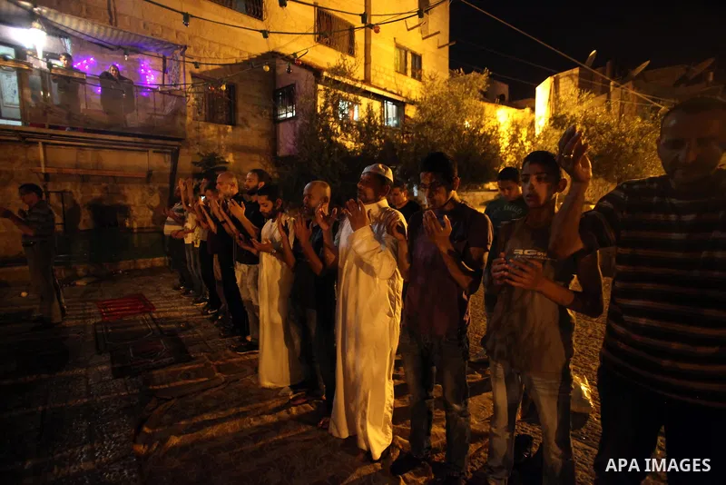 Palestinian muslim worshipers pray outside the al-Aqsa mosque compound as Israeli policemen barring entrance to the al-Aqsa mosque to men younger than 50 years, to mark Laylat al-Qadr, or Night of Destiny, in Jerusalem's...
