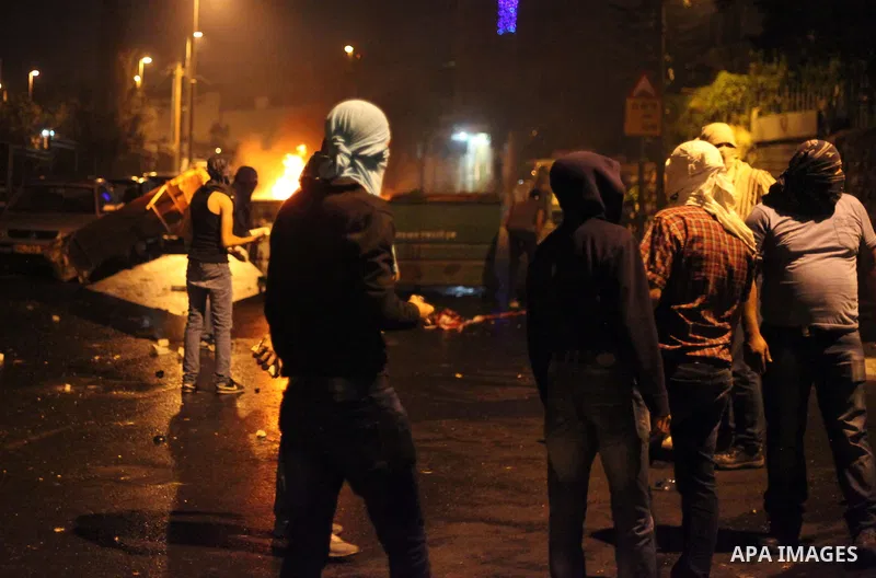 Palestinian protesters throw stones at Israeli policemen as they barring entrance to the al-Aqsa mosque to men younger than 50 years, to mark Laylat al-Qadr, or Night of Destiny, in Jerusalem's Old City on July 24, 2014....