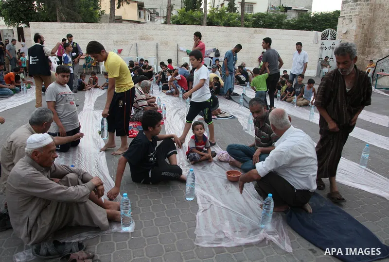 Displaced Palestinian gather of Iftar meal at a Greek Orthodox church where many Palestinians are taking shelter in Gaza City on July 25, 2014. US Secretary of State John Kerry entered new meetings with UN chief Ban Ki-m...