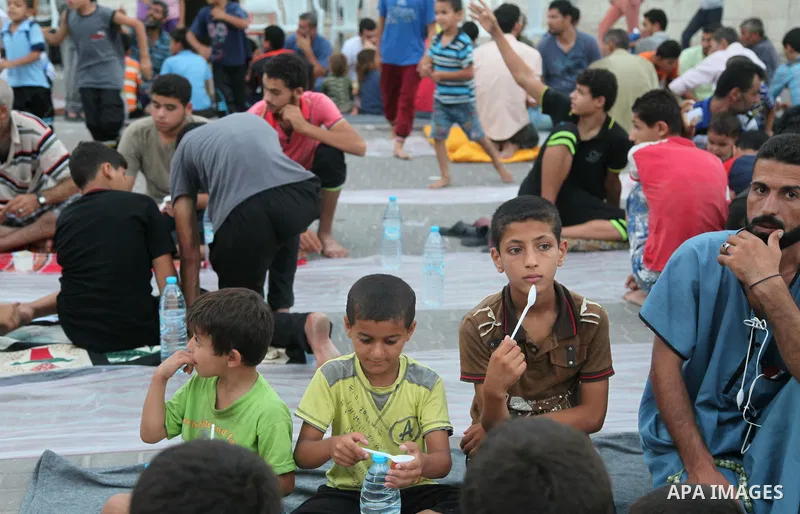 Displaced Palestinian gather of Iftar meal at a Greek Orthodox church where many Palestinians are taking shelter in Gaza City on July 25, 2014. US Secretary of State John Kerry entered new meetings with UN chief Ban Ki-m...