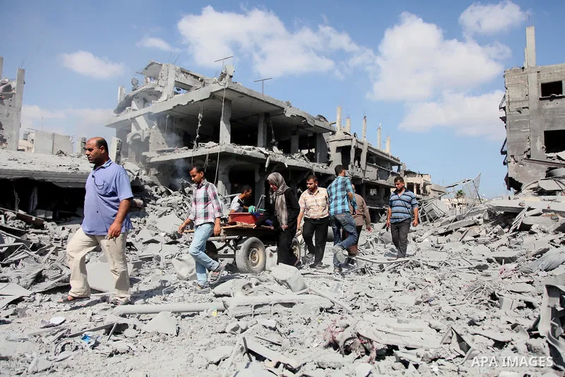 Palestinians walk on the rubble as they enter the northern district of Beit Hanun to check their homes in the Gaza Strip during an humanitarian truce on July 26, 2014. Palestinians retrieved dozens of bodies from the rub...