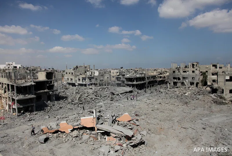 Palestinians walks over the debris of buildings in the northern district of Beit Hanun in the Gaza Strip during an humanitarian truce on July 26, 2014. The bodies of at least another 35 Palestinians were recovered from r...