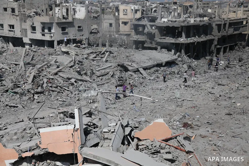 Palestinians walks over the debris of buildings in the northern district of Beit Hanun in the Gaza Strip during an humanitarian truce on July 26, 2014. The bodies of at least another 35 Palestinians were recovered from r...