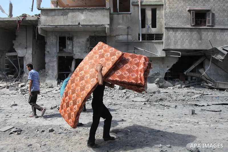 A Palestinian man carries his belongings from her destroyed house in the northern district of Beit Hanun in the Gaza Strip during an humanitarian truce on July 26, 2014. The bodies of at least another 35 Palestinians wer...