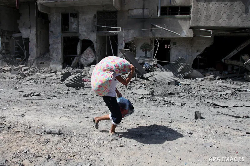 A Palestinian man carries his belongings from her destroyed house in the northern district of Beit Hanun in the Gaza Strip during an humanitarian truce on July 26, 2014. The bodies of at least another 35 Palestinians wer...